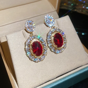 Detail of luxury oval red ruby earrings with gold plating and sparkling zircon stones