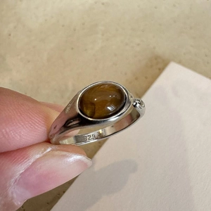 Vintage S925 silver ring with brown oval resin stone shown in a close-up hand-held view