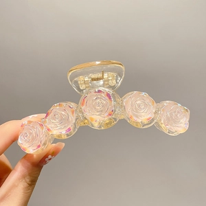 Detailed close-up of iridescent resin rose hair claw clip with golden metal spring