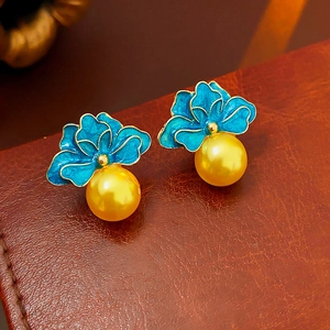 Macro detail of vintage blue enamel flower earrings with a large golden pearl drop