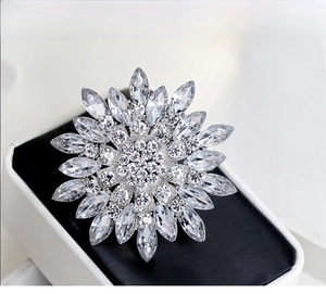 Detailed close-up of a silver flower brooch with sparkling crystals on a gift box