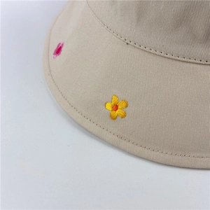 Close-up of small floral embroidery on a beige cotton sun hat with clean stitching