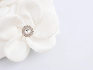 Detailaufnahme der weißen Satin-3D-Blume mit funkelndem Strass-Zentrum für Damen