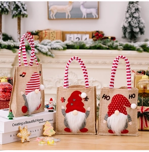 Detailed view of three burlap Christmas gift bags featuring festive gnome characters