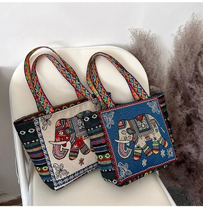 Close-up of two ethnic canvas tote bags with elephant embroidery in beige and blue