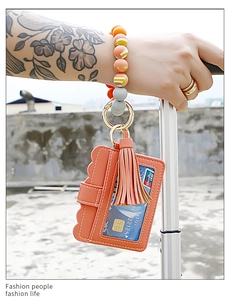 Detail of orange PU leather card holder with silicone bead wristlet on a luggage handle