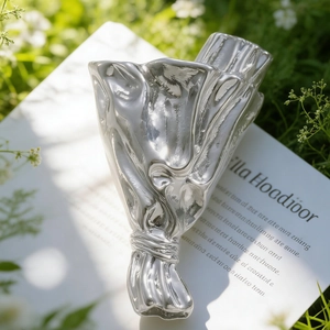 Detail of creative silver bouquet brooch with a wrinkled texture on white paper props