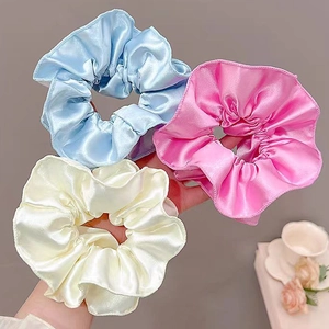 Three elegant cream satin hair scrunchies in blue, pink, and beige for ballet style buns