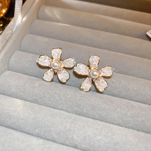 Close-up of gold flower earrings with crushed ice texture and pearl center on velvet