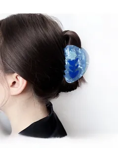 Blue marble acetate hair claw clip with floral pattern shown on hair from a side view