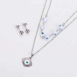 Detail view of a double-layered stainless steel evil eye necklace and silver ball earrings
