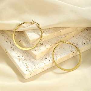 Minimalist gold plated stainless steel large hoop earrings on elegant stone background