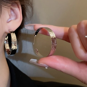 Close-up of silver textured hoop earrings featuring irregular hammered metal finish