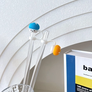 Detail of blue and orange mushroom silicone straw covers on transparent glass straws