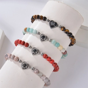 Detail of four colorful stone bead bracelets with heart-shaped 100 languages projection charm
