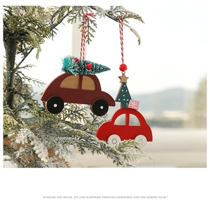 Détail de pendentifs de voiture de Noël en bois suspendus sur des branches de pin enneigées