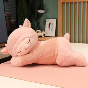 Detailed close-up of a pink plush sheep toy wearing a soft knitted sweater in a home setting