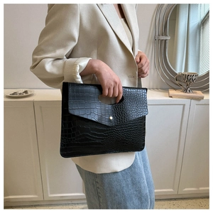 Close-up of black crocodile pattern tote bag with golden metal hardware detail