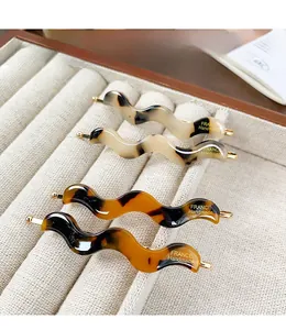 Detail of four acetate wave hair clips with tortoiseshell patterns and gold handmade logo