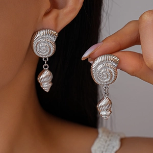 Elegant silver conch shell drop earrings with metallic texture worn on a model