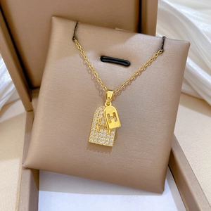 Detail of double-layer titanium necklace featuring H pendant with sparkling crystals