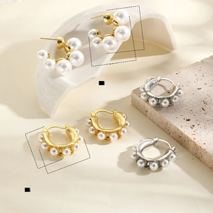Detail of 18k gold plated U-shaped earrings with faux pearls on stone background