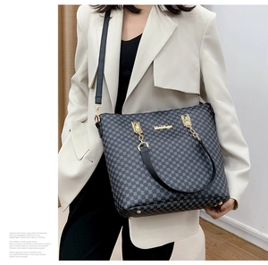 Detail of grid pattern tote bag with gold chain strap and metallic brand logo plate