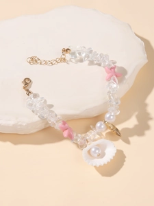 Close-up of beach bracelet with seashell pendant, pink starfish, and faux pearls on stone