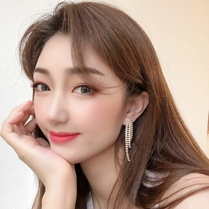 Close-up of luxury gold-plated long tassel earrings with sparkling rhinestones on model