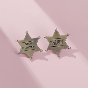 Close-up of hexagonal star badges with DILF HUNTER and SHERIFF text in metal