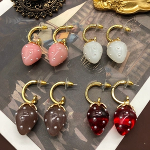 Detailed view of four colorful strawberry pendant earrings on a vintage art background