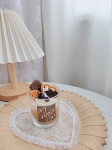 Detail of strawberry chocolate sundae candle in glass jar on a wooden tray with lace