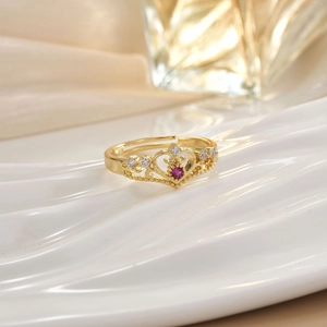 Detail of a golden crown ring with red heart gemstone and micro-pave crystals