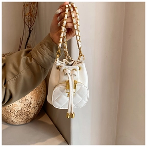 Detail of white quilted mini bucket bag with gold chain strap and drawstring closure