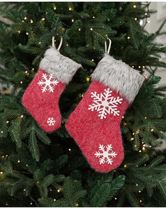 Close-up of red Christmas stockings with white snowflakes hanging on a lit Xmas tree