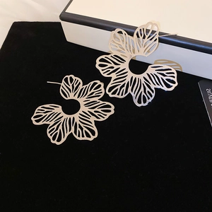 Macro shot of silver hollow flower stud earrings with intricate vein details and metallic shine