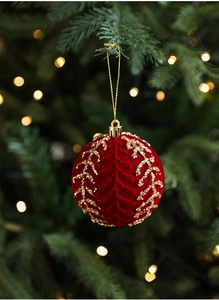 Close-up of a burgundy flocked Christmas ball with gold sequins on a festive tree