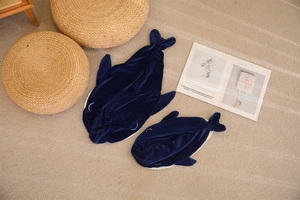Deep blue plush whale sleeping bags in two sizes shown on a cozy home rug