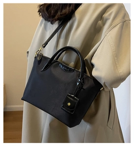 Detail of black waterproof Oxford cloth tote bag with leather handles and Clear X logo