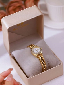 Close-up of a gold-toned women's watch with crystal bezel and white dial in a gift box
