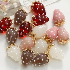 Detailed view of handmade resin strawberry charms with small pearls and gold leaf hooks