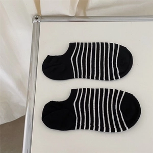 Detail of low cut black boat socks with white stripes and delicate floral embroidery