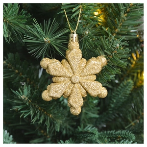 Close-up of golden glitter snowflake ornament hanging on a green Christmas tree branch