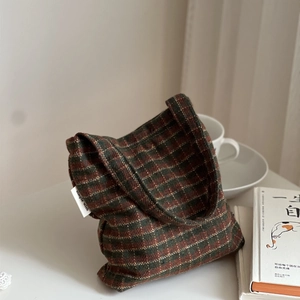 Detail of plaid wool fabric tote with a minimalist side label in a cozy setting