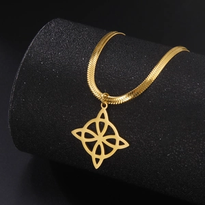 Close-up of golden Witch's Knot pendant on sleek snake chain over a black textured stand
