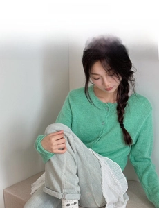 Detail of green knit cardigan with round neck and matching buttons in a soft casual style