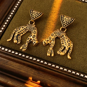 Detailed view of vintage leopard earrings in gold finish on green velvet surface