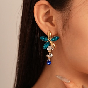 Detail of flower stud earrings with peacock blue crystals and teardrop tassels on model
