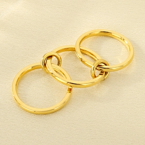 Close-up of three interlocking gold stainless steel rings on a silk texture fabric