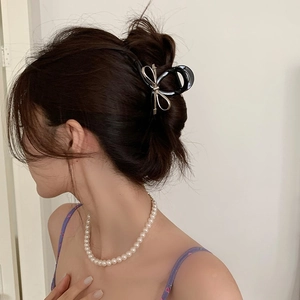 Elegant large black butterfly hair claw clip with gold trim on model with pearls